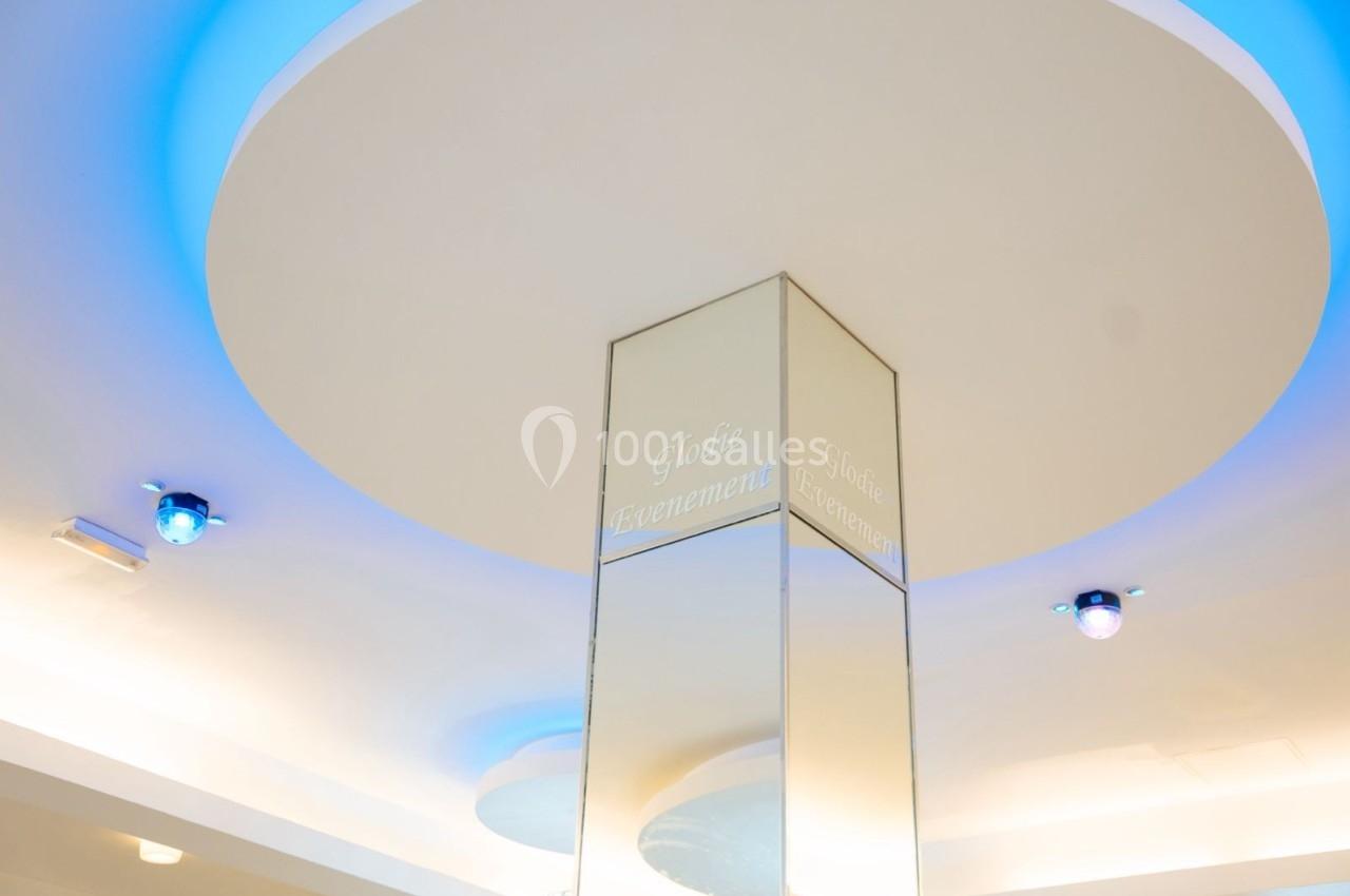 Location salle Viry-Châtillon (Essonne) - Glodie Evènements #10 Plafond lumineux avec éclairage bleu et blanc, reflété par une colonne en miroir au centre.