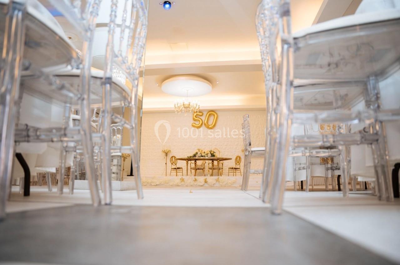 Location salle Viry-Châtillon (Essonne) - Glodie Evènements #11 Salle décorée pour une célébration avec des chaises transparentes, une table ornée et le chiffre 50 en ballons dorés.