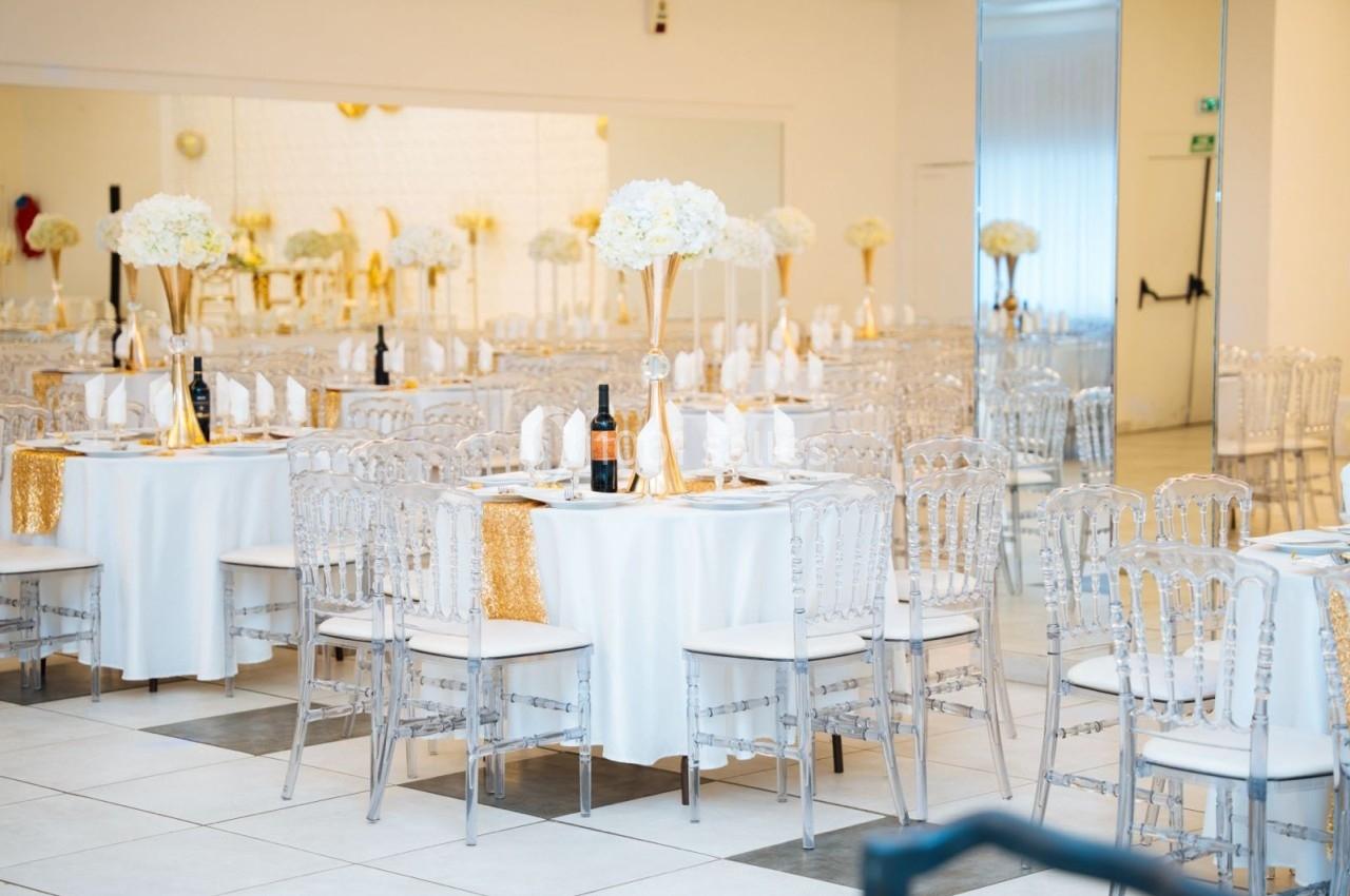 Location salle Viry-Châtillon (Essonne) - Glodie Evènements #12 Salle de réception élégante avec tables dressées, nappes blanches, chaises transparentes et centres de table fleuris.