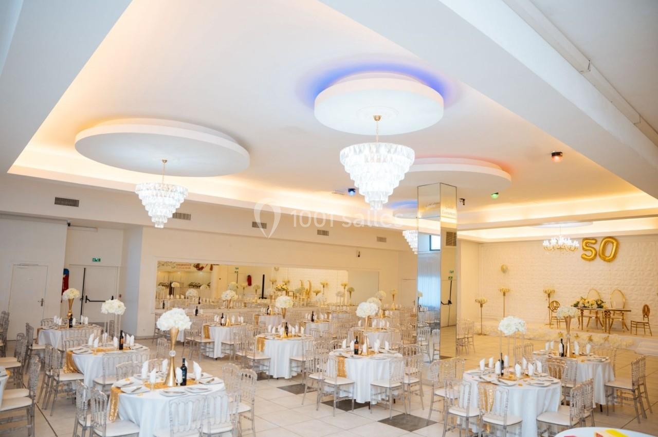 Location salle Viry-Châtillon (Essonne) - Glodie Evènements #14 Salle de réception élégante décorée en blanc et or avec tables dressées, chandeliers et chiffre 50 en arrière-plan.