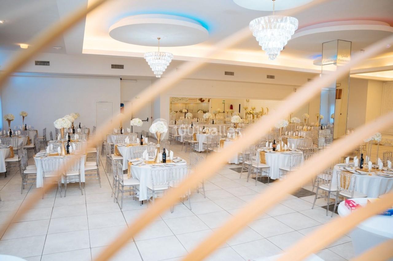 Location salle Viry-Châtillon (Essonne) - Glodie Evènements #16 Salle de réception élégante avec tables dressées, décorations florales blanches et lustres suspendus.