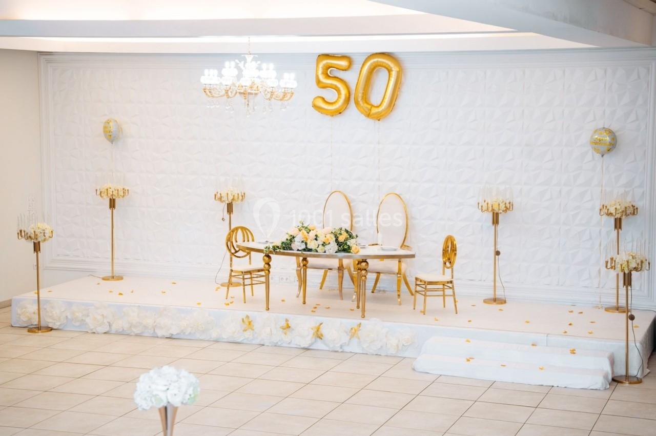 Location salle Viry-Châtillon (Essonne) - Glodie Evènements #17 Salle décorée pour un 50e anniversaire avec ballons dorés, table ornée de fleurs et chaises élégantes sur une estrade…