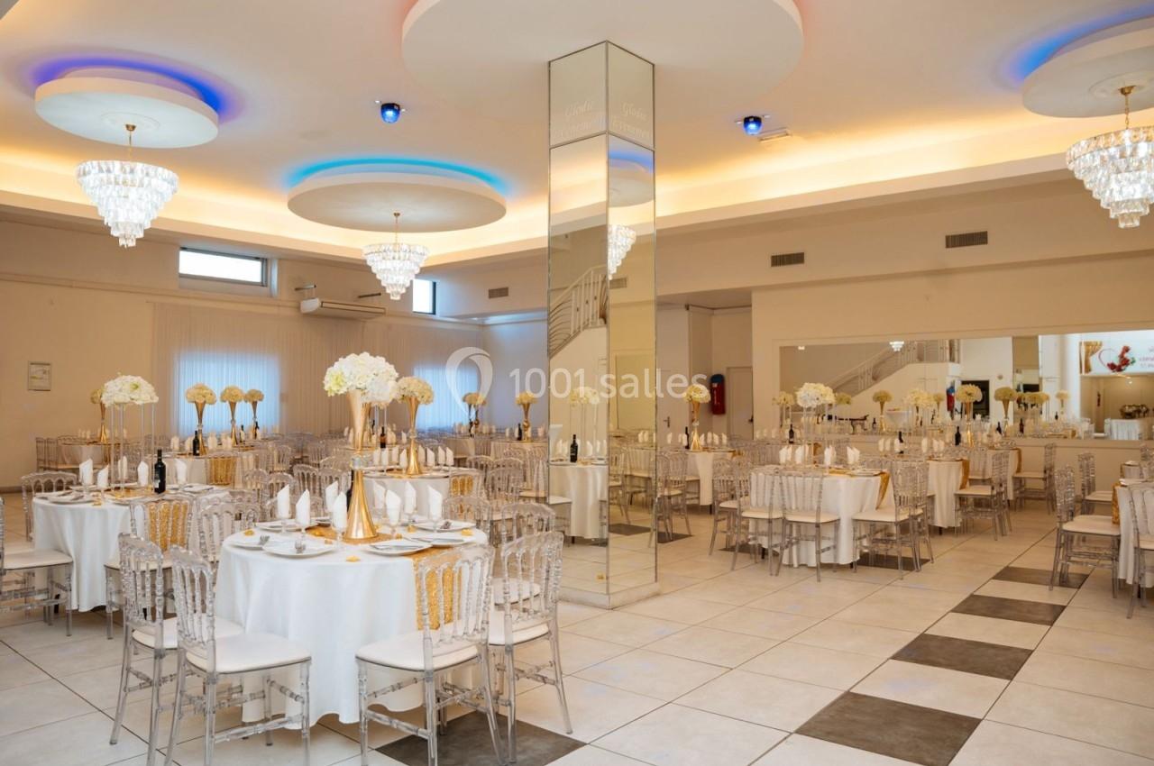 Location salle Viry-Châtillon (Essonne) - Glodie Evènements #18 Salle de réception élégante avec tables rondes dressées, chaises transparentes et décorations florales blanches.