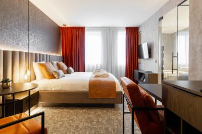 Chambre d'hôtel moderne avec lit double, salle de bain vitrée, lavabo double et lumière naturelle.