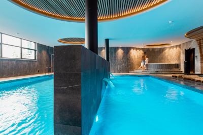 Chambre d'hôtel moderne avec lit double, salle de bain vitrée, lavabo double et lumière naturelle.