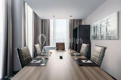 Miniature Location salle Mons (Hainaut) - Congrès Hôtel Mons Van Der Valk #3 Salle de réunion moderne avec table rectangulaire, chaises noires, écran mural, tableau blanc et minibar.