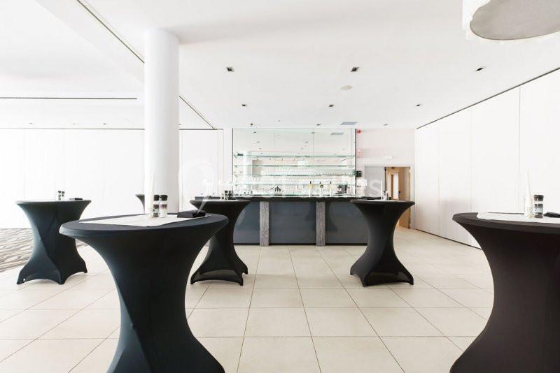 Location salle Mons (Hainaut) - Congrès Hôtel Mons Van Der Valk #6 Salle lumineuse avec tables hautes noires et un bar moderne en arrière-plan.