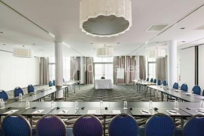 Miniature Location salle Mons (Hainaut) - Congrès Hôtel Mons Van Der Valk #8 Salle de réunion moderne avec table rectangulaire, chaises noires, écran mural, tableau blanc et minibar.