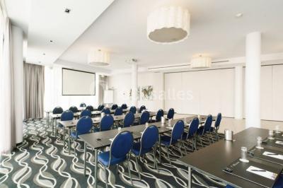 Miniature Location salle Mons (Hainaut) - Congrès Hôtel Mons Van Der Valk #11 Salle de réunion moderne avec table rectangulaire, chaises noires, écran mural, tableau blanc et minibar.