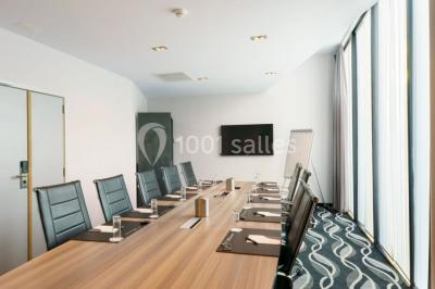 Miniature Location salle Mons (Hainaut) - Congrès Hôtel Mons Van Der Valk #14 Salle de réunion moderne avec table rectangulaire, chaises noires, écran mural, tableau blanc et minibar.