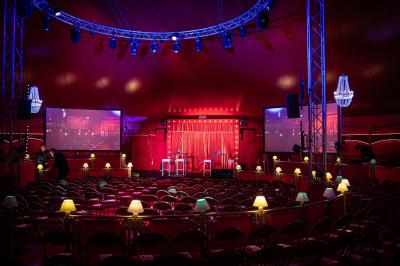 Un acrobate réalise une figure sur un tissu aérien sous un chapiteau éclairé par des lumières colorées.