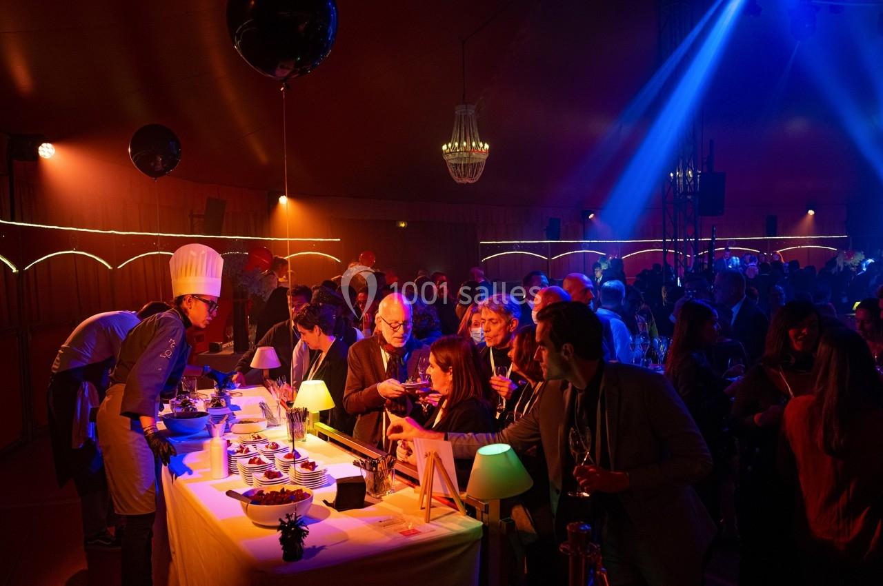 Des convives se servent à un buffet éclairé dans une ambiance festive avec des lumières colorées.