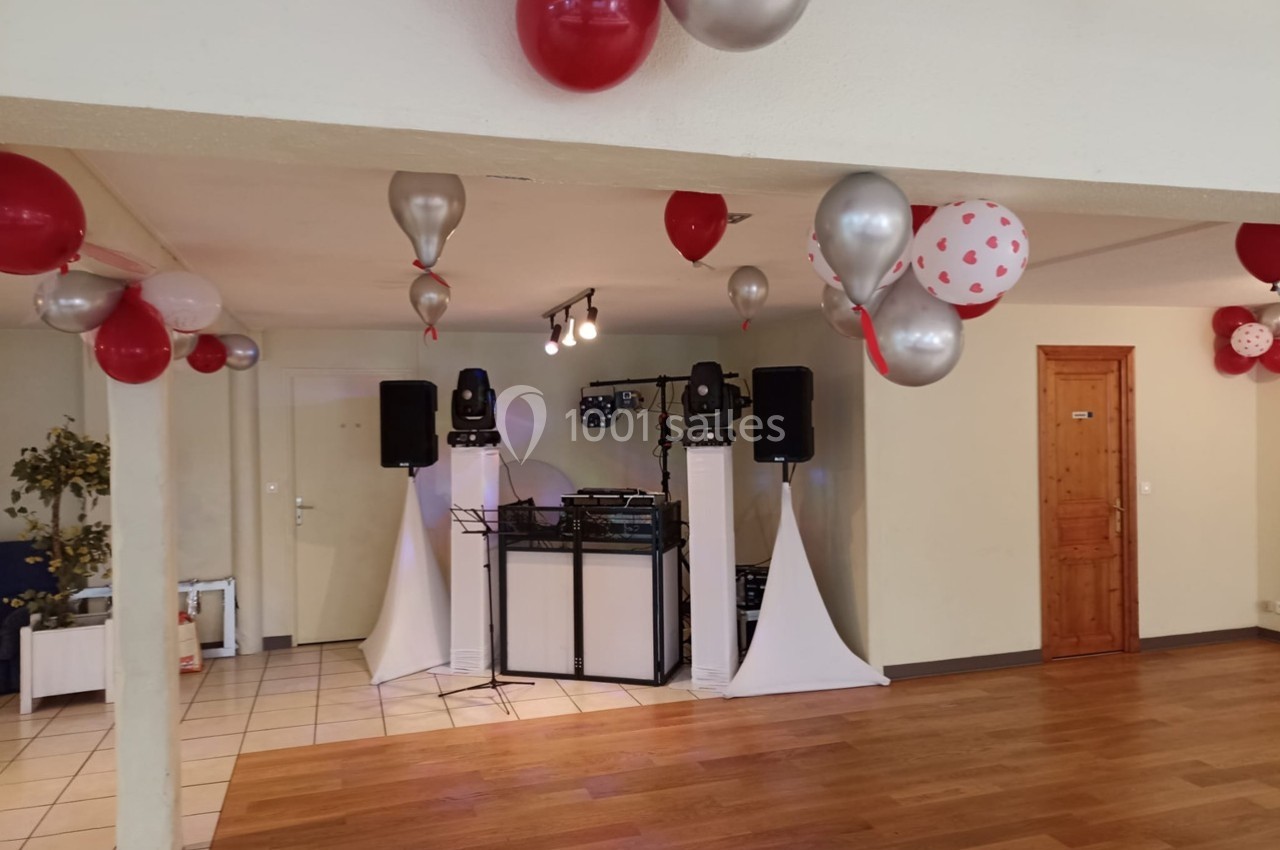Salle décorée avec des ballons rouges, blancs et argentés, équipée d'une installation sonore et d'un parquet en bois.