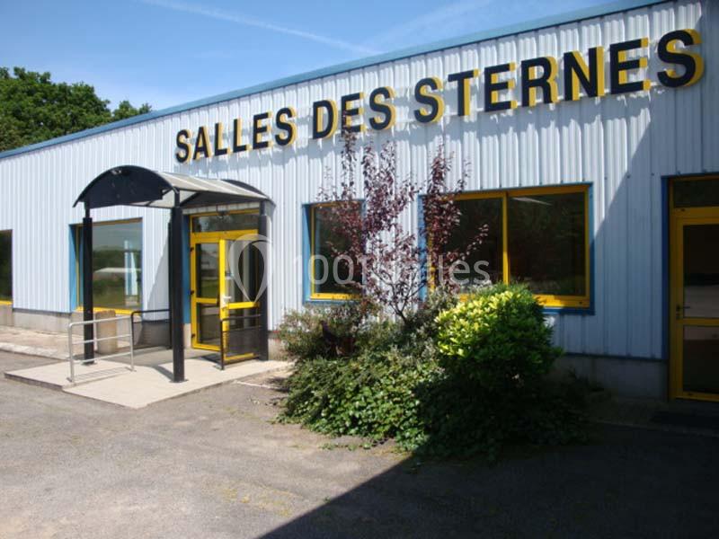 Façade d'un bâtiment avec l'enseigne ’Salles des Sternes’, entrée vitrée et végétation à l'avant.