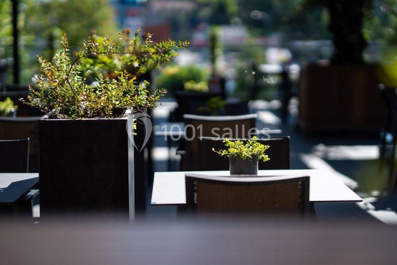 Location salle Nivelles (Brabant wallon) - Hôtel Nivelles Sud #16 Terrasse extérieure avec tables, chaises et plantes en pot, éclairée par une lumière naturelle.
