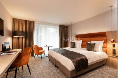 Miniature Location salle Nivelles (Brabant wallon) - Hôtel Nivelles Sud #11 Bornes de recharge électriques Tesla alignées sur un parking, entourées de végétation et de voitures en arrière-plan.