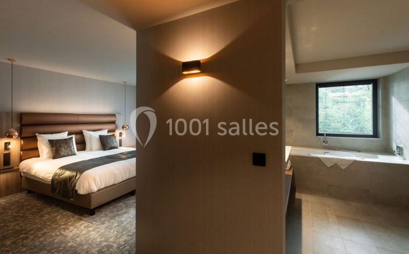 Location salle Nivelles (Brabant wallon) - Hôtel Nivelles Sud #10 Chambre d'hôtel moderne avec lit double, éclairage tamisé et salle de bain attenante avec baignoire près d'une fenêtre.