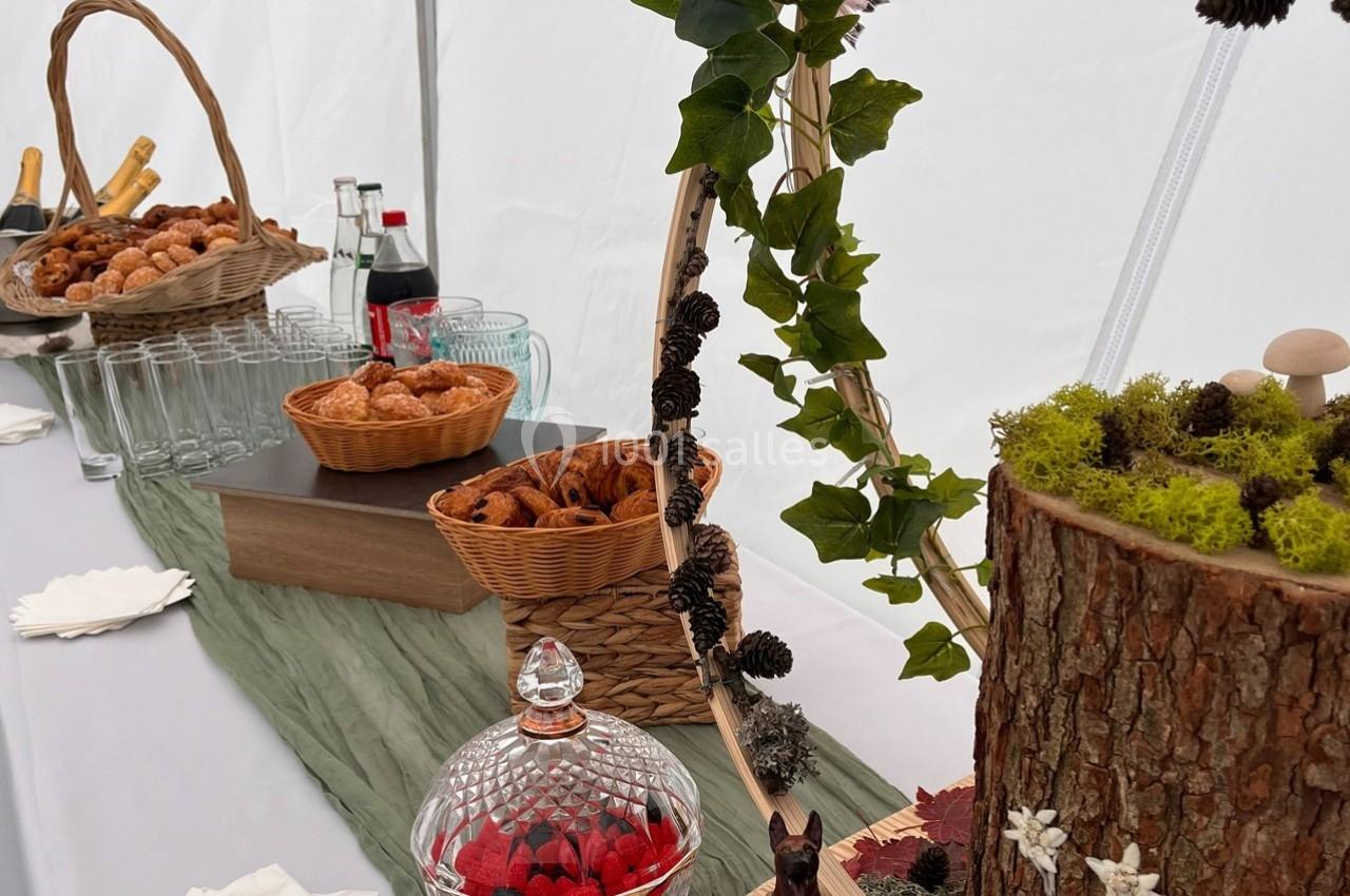 Table décorée avec des éléments naturels, contenant des viennoiseries, des boissons et des décorations en bois et mousse.