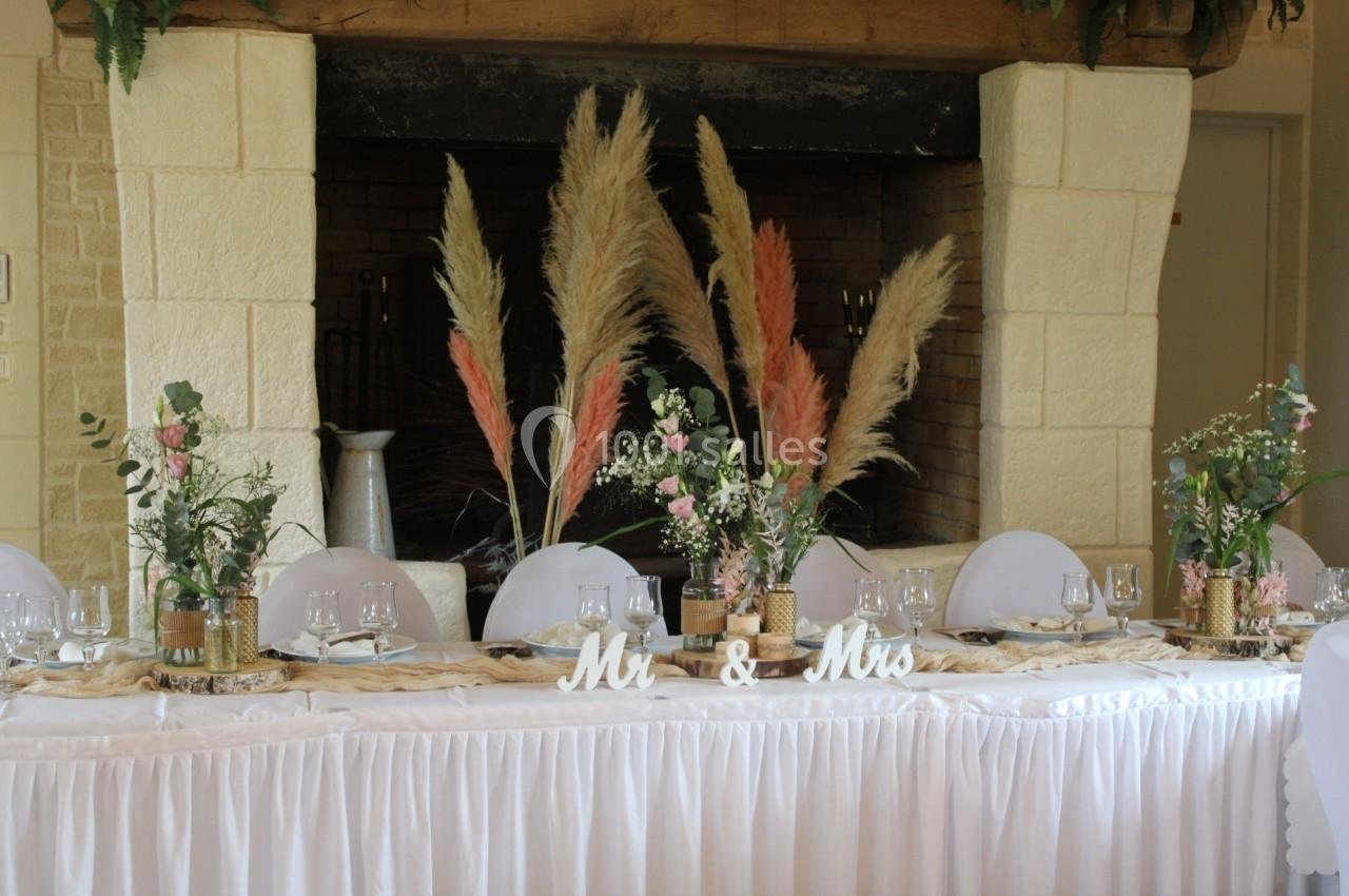 Table décorée pour un mariage avec des fleurs, des herbes de la pampa et une cheminée en arrière-plan.