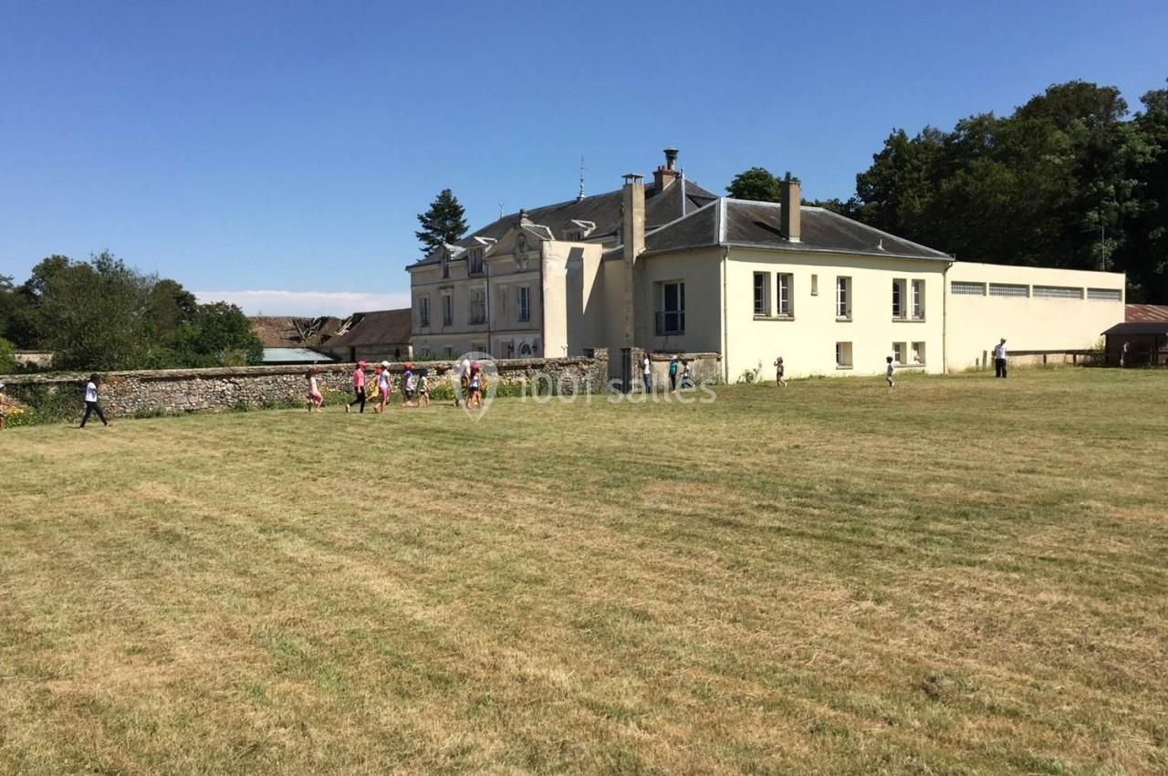 Un groupe de personnes marche sur une pelouse devant un grand bâtiment blanc entouré d'arbres.