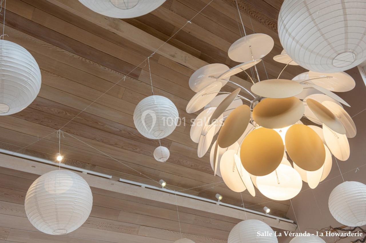 Suspension lumineuse design entourée de lanternes en papier blanc, accrochées au plafond en bois clair.