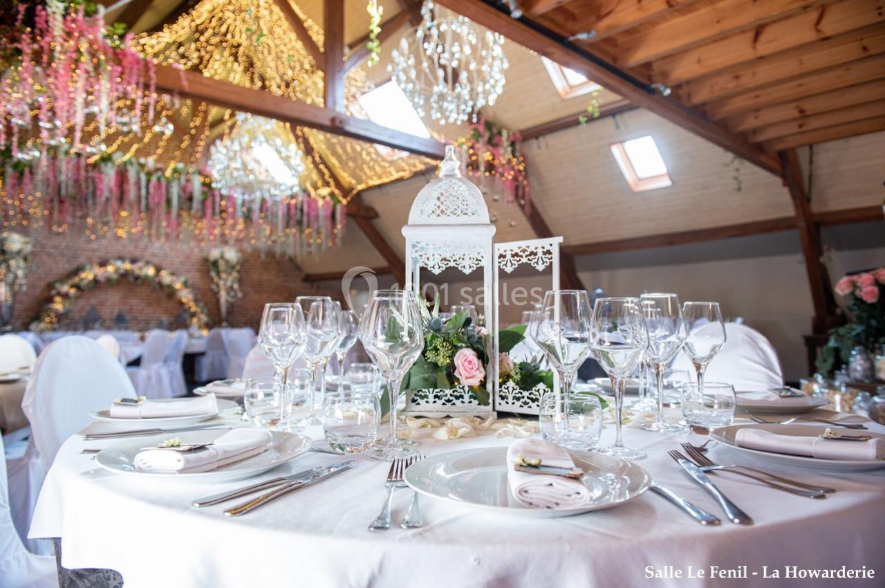 Table élégamment dressée avec vaisselle raffinée, décoration florale et lanterne blanche dans une salle de réception…
