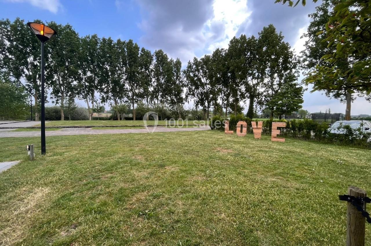 Pelouse verdoyante avec des arbres en arrière-plan et des lettres formant le mot ’LOVE’ posées sur l'herbe.