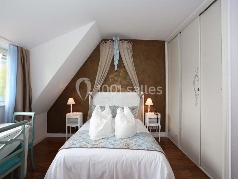 Chambre lumineuse avec lit double, draperies décoratives, tables de chevet et placard coulissant dans un décor chaleureux.