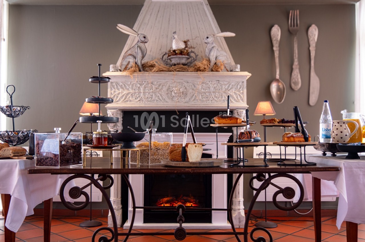 Table garnie de desserts variés devant une cheminée décorée de lapins et d'ustensiles de cuisine géants.