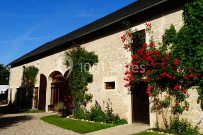 Tente rouge et blanche abritant des tables dressées avec nappes et décorations pour un repas en extérieur.