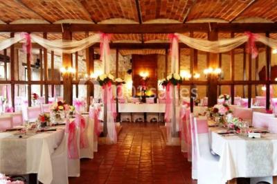 Tente rouge et blanche abritant des tables dressées avec nappes et décorations pour un repas en extérieur.