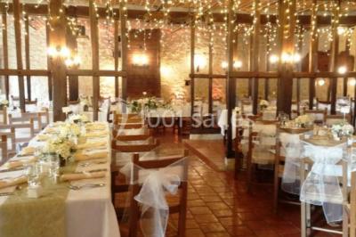 Tente rouge et blanche abritant des tables dressées avec nappes et décorations pour un repas en extérieur.