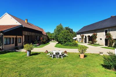 Tente rouge et blanche abritant des tables dressées avec nappes et décorations pour un repas en extérieur.