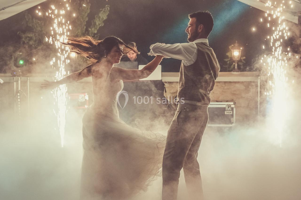 Un couple danse sous une tente décorée, entouré de fumée et d'étincelles dans une ambiance festive.