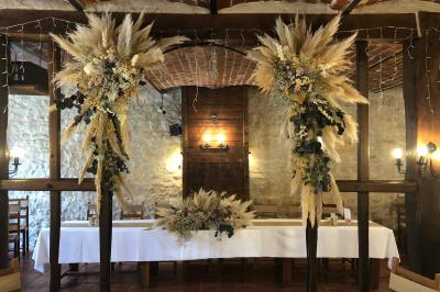 Tente rouge et blanche abritant des tables dressées avec nappes et décorations pour un repas en extérieur.