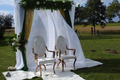 Tente rouge et blanche abritant des tables dressées avec nappes et décorations pour un repas en extérieur.