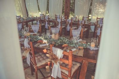 Tente rouge et blanche abritant des tables dressées avec nappes et décorations pour un repas en extérieur.
