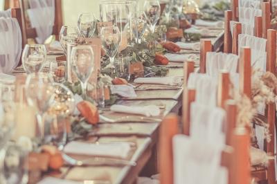 Tente rouge et blanche abritant des tables dressées avec nappes et décorations pour un repas en extérieur.