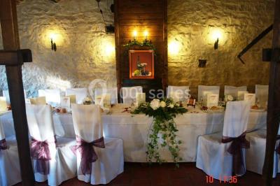 Tente rouge et blanche abritant des tables dressées avec nappes et décorations pour un repas en extérieur.