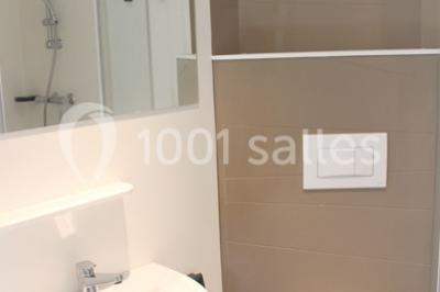 Deux personnes jouent au tennis sur un court extérieur entouré d'arbres par une journée ensoleillée.