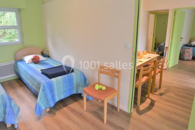 Deux personnes jouent au tennis sur un court extérieur entouré d'arbres par une journée ensoleillée.