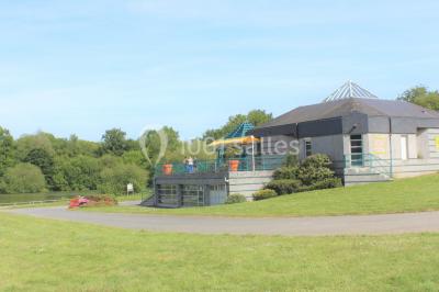 Deux personnes jouent au tennis sur un court extérieur entouré d'arbres par une journée ensoleillée.