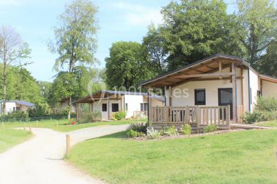 Deux personnes jouent au tennis sur un court extérieur entouré d'arbres par une journée ensoleillée.