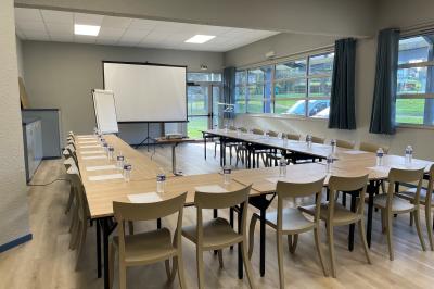 Deux personnes jouent au tennis sur un court extérieur entouré d'arbres par une journée ensoleillée.