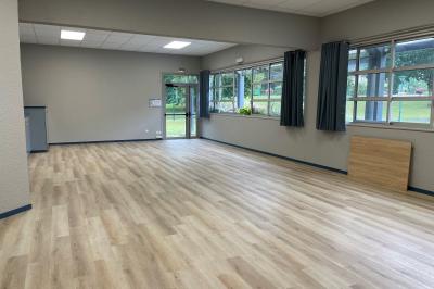 Deux personnes jouent au tennis sur un court extérieur entouré d'arbres par une journée ensoleillée.