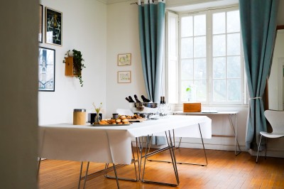 Plantes d'intérieur variées dans des pots en verre et en métal doré, disposées sur une cheminée en marbre noir.