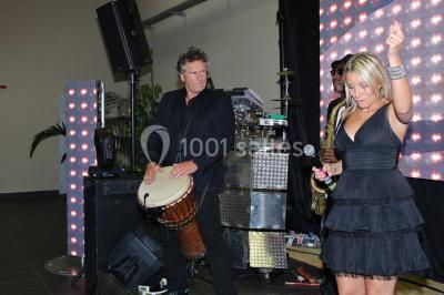 Miniature Location salle Saint-Maximin (Oise) - L'Art d'Oise #26 Salle décorée pour un événement, avec des tables rondes dressées, chaises rouges et un fond floral rose.