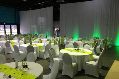 Miniature Location salle Saint-Maximin (Oise) - L'Art d'Oise #15 Salle décorée pour un événement, avec des tables rondes dressées, chaises rouges et un fond floral rose.