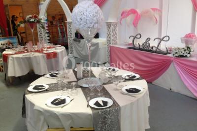 Miniature Location salle Saint-Maximin (Oise) - L'Art d'Oise #25 Salle décorée pour un événement, avec des tables rondes dressées, chaises rouges et un fond floral rose.