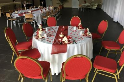 Miniature Location salle Saint-Maximin (Oise) - L'Art d'Oise #22 Salle décorée pour un événement, avec des tables rondes dressées, chaises rouges et un fond floral rose.